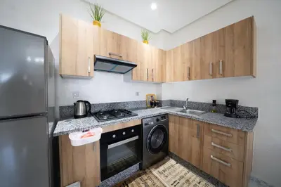 a kitchen with wooden cabinets and a washer and dryer at Studio Confortable avec Balcon, Piscine, Jardin et Aire de Jeux in Casablanca