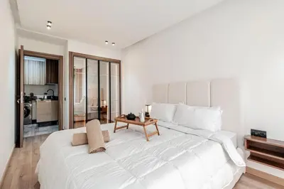 a white bedroom with a large bed and a table at Maârif Elegance et confort in Casablanca