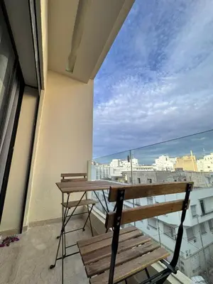 a balcony with a wooden table and chairs and a view at Nova Casa in Casablanca