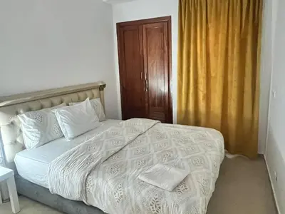 a bedroom with a white bed with a wooden cabinet at La Parenthèse de CASABLANCA in Casablanca