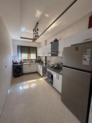 a large kitchen with a refrigerator and a stove at Comfortable and quiet apartment with Buzzinga in Bouznika