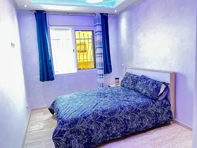 a bedroom with a bed with blue sheets and a window at Comfortable, quiet and beach apartment in Skhirat