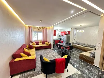 a living room with a red couch and chairs at Apartment 1 CH près de la plage in Oulad Akkou