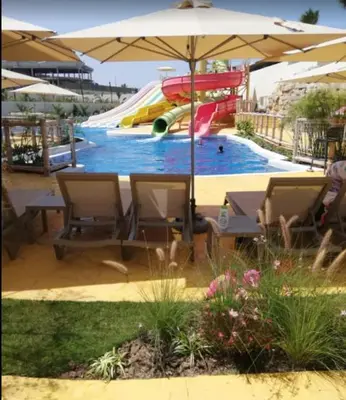 a pool with a slide and an umbrella at Apartment 1 CH près de la plage in Oulad Akkou