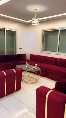 a living room with a red couch and a table at Charming apartment in Mansoria in Mohammedia