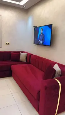 a red couch in a living room with a flat screen tv at Charming apartment in Mansoria in Mohammedia