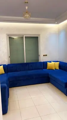 a blue couch in a living room with yellow pillows at Charming apartment in Mansoria in Mohammedia
