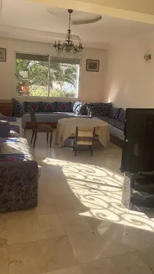 a living room with a table and a couch and a tv at Villa à louer nouaceur 3 chambres in Nouaseur