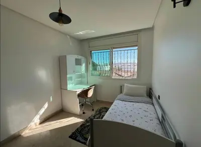 a bedroom with a bed and a desk and window at Appartement à 2mn gare tgv Agdal in Rabat
