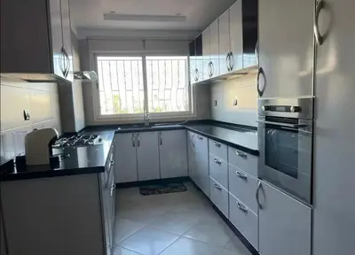 a kitchen with white cabinets and black counter tops at Appartement à 2mn gare tgv Agdal in Rabat