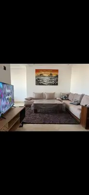 a living room with a couch and a flat screen tv at Appartement à 2mn gare tgv Agdal in Rabat
