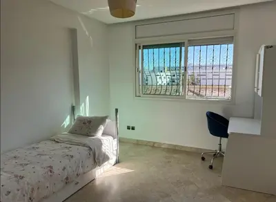 a bedroom with a bed and a desk and a window at Appartement à 2mn gare tgv Agdal in Rabat
