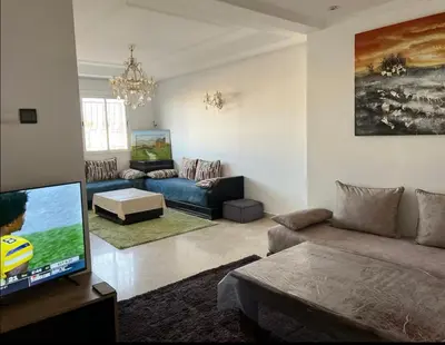 a living room with a couch and a flat screen tv at Appartement à 2mn gare tgv Agdal in Rabat