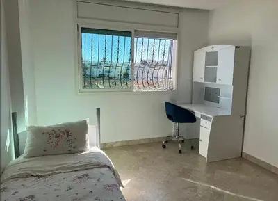 a bedroom with a bed and a desk and a window at Appartement à 2mn gare tgv Agdal in Rabat