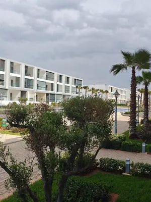 a large white building with palm trees in front of it at Casa Atlantica mit Meerblick und Poolparadies in Mansouria