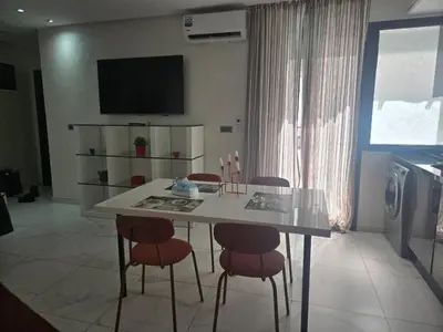 a kitchen with a table with chairs and a television at Tounarouz Studio in Casablanca