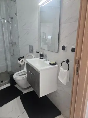 a white bathroom with a toilet and a sink at Tounarouz Studio in Casablanca