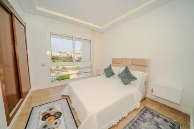 a white bedroom with a bed and a window at Rabat Apartment in Rabat
