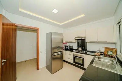 a kitchen with a stainless steel refrigerator and white cabinets at Rabat Apartment in Rabat