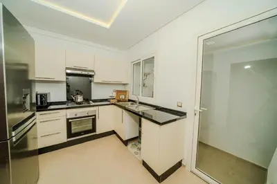a kitchen with white cabinets and a stainless steel refrigerator at Rabat Apartment in Rabat