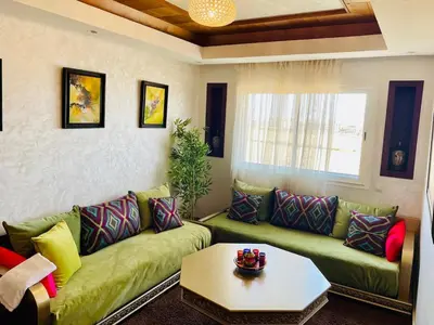 a living room with a green couch and a table at Janat KLK, tamaris beach in Tamaris