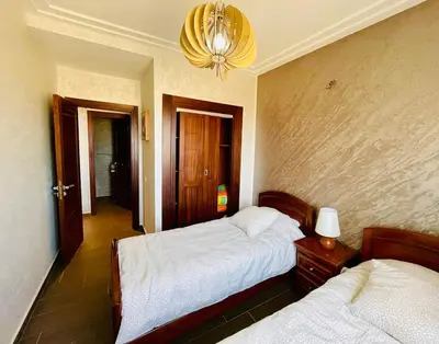 a bedroom with two beds and a chandelier at Janat KLK, tamaris beach in Tamaris