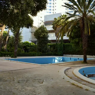 an empty swimming pool with palm trees and a building at tanger in Aïn Diab