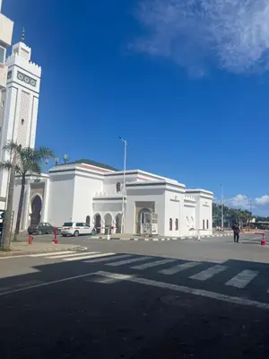 a white building with a clock tower on a street at Vue mer, confort, plage à 10 min in Sidi Rahal