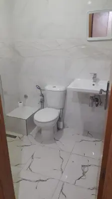 a white bathroom with a toilet and a sink at Chez Fatima - Nassim Gh12 in Mohammedia