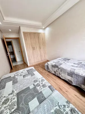 a bedroom with two beds and a rug at Residence Garden Paradise plage luxe in Bouznika