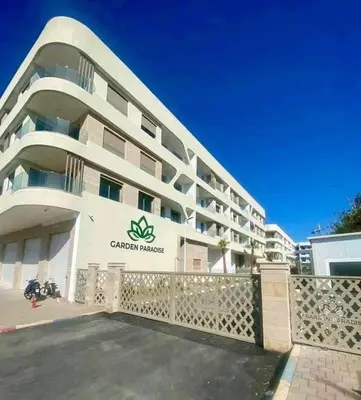 a large white building with a sign on it at Residence Garden Paradise plage luxe in Bouznika