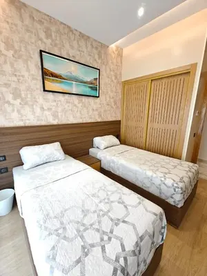 a bedroom with two beds and a picture on the wall at Appart Moderne Vue mer latérale & piscine - Plage des Sablettes El Mansouria in O Ben Slimane