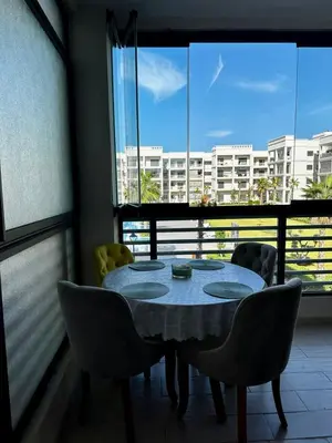 a table and chairs in a room with a large window at APT Luxueux à Costa Beach 3 avec Piscine et accès Plage in Bouznika