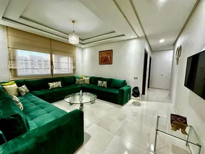 a living room with a green couch and a table at APT Luxueux à Costa Beach 3 avec Piscine et accès Plage in Bouznika