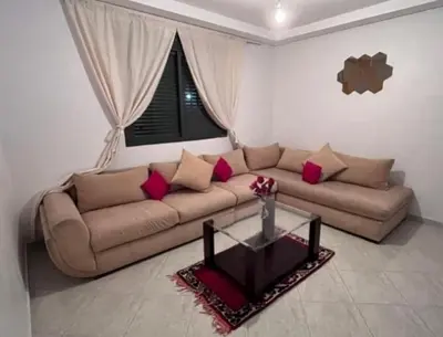 a living room with a brown couch with red pillows at En face hôpital M6,Proche Aéroport et nearchore in Oulad Akkou