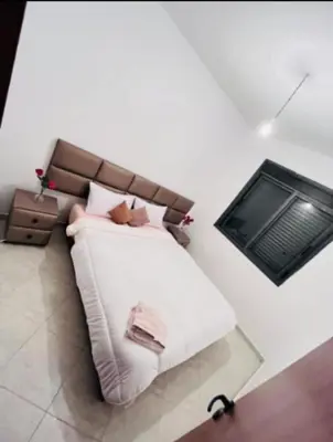 a bedroom with a white bed with a brown headboard at En face hôpital M6,Proche Aéroport et nearchore in Oulad Akkou