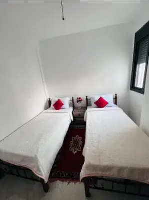 two beds in a room with red pillows at En face hôpital M6,Proche Aéroport et nearchore in Oulad Akkou