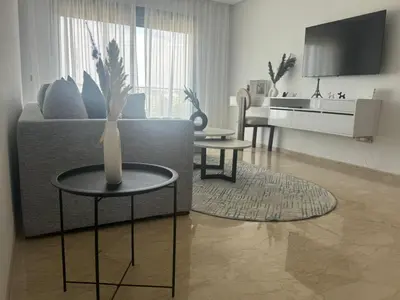 a living room with a couch and a table with a vase at Appart idéal Face Gare Agdal in Rabat