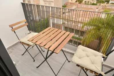 a wooden bench and two chairs on a balcony at Antonio Cerezo in Maarif