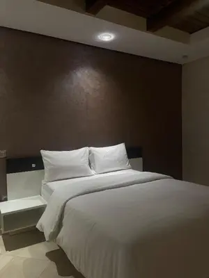 a bedroom with a large bed with white sheets at coastal charm harhoura in Temara