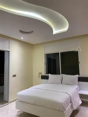 a bedroom with a large white bed and a ceiling at coastal charm harhoura in Temara