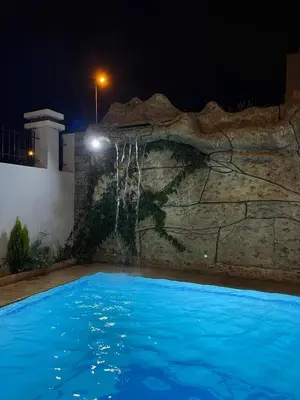 a swimming pool at night with a waterfall at coastal charm harhoura in Temara