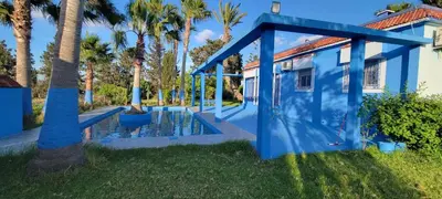 a blue house with palm trees in the yard at Auberge Abrar in O Ben Slimane