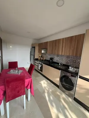 a kitchen with a red table and chairs in a room at Appartement cosy et confortable in Casablanca