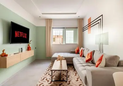 a living room with a couch and a tv at Appartement de luxe 2 chambres PS5,AC,Fibre,Netflix à agdal Au coeur de Rabat in Rabat