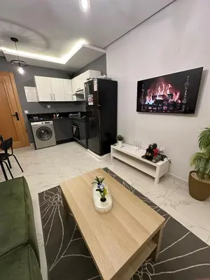 a living room with a table and a tv on the wall at Chic Studio In The Heart of Casablanca Morocco in Casablanca