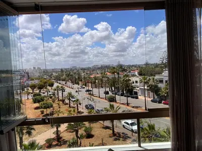 a window with a view of a street and palm trees at Grand appartement la corniche vue panoramique sur Casablanca in Casablanca