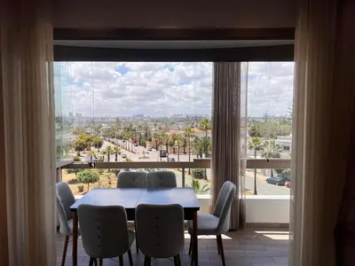 a dining room with a table and chairs and a large window at Grand appartement la corniche vue panoramique sur Casablanca in Casablanca