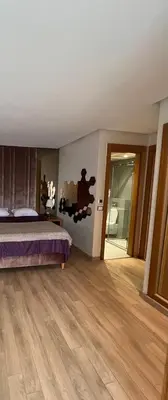 a bedroom with a bed and a wooden floor at Grand appartement la corniche vue panoramique sur Casablanca in Casablanca