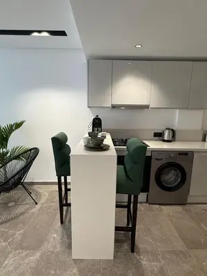 a kitchen with a white counter and green chairs at Adresse exceptionnelle Casablanca in Casablanca